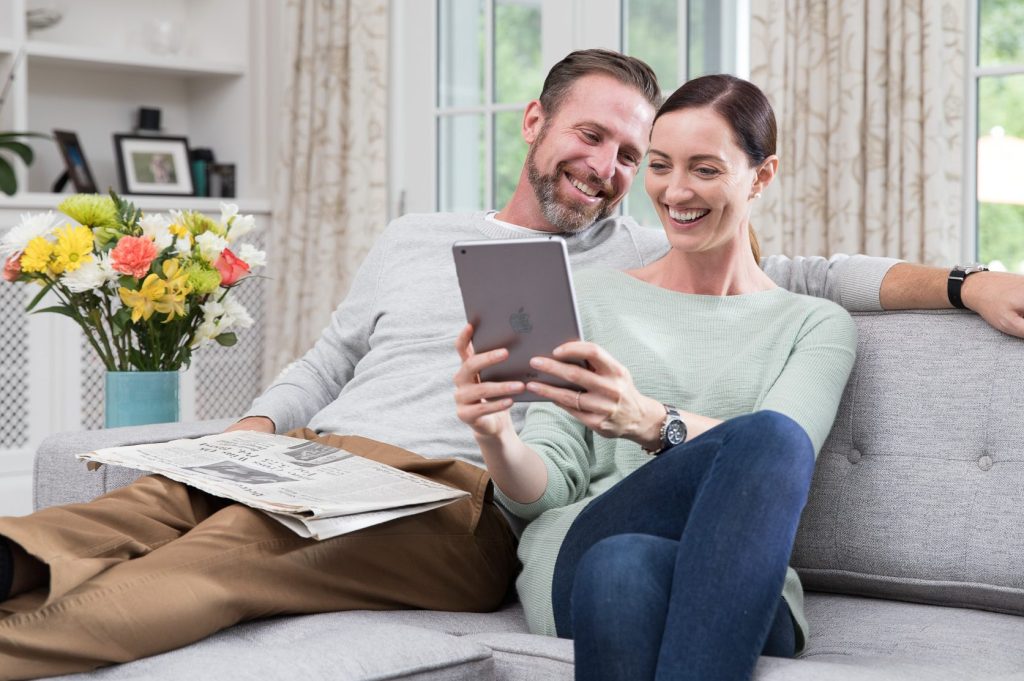 A couple reviews The Ultimate Home Inspection report from Pillar to Post together while sitting on a couch in their new home.