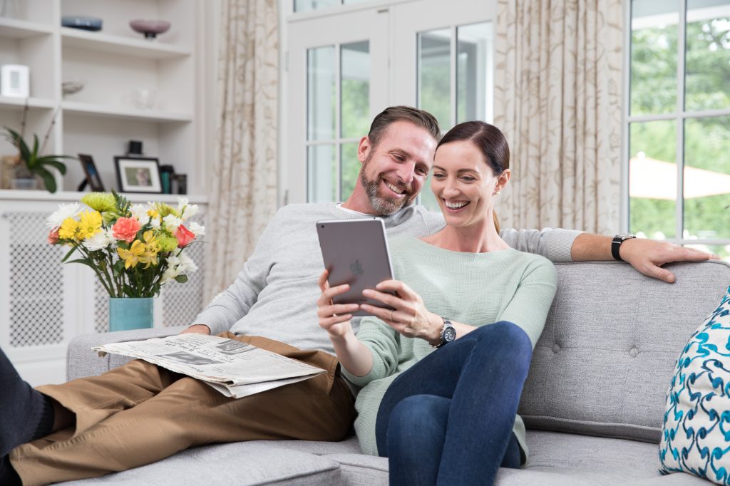 Man and woman sit on a couch reviewing their PTPHomeManual on a couch.